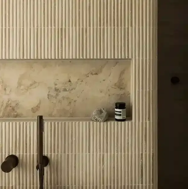 Close up of fluted wall tiles, stone niche and brushed bronze tapware
