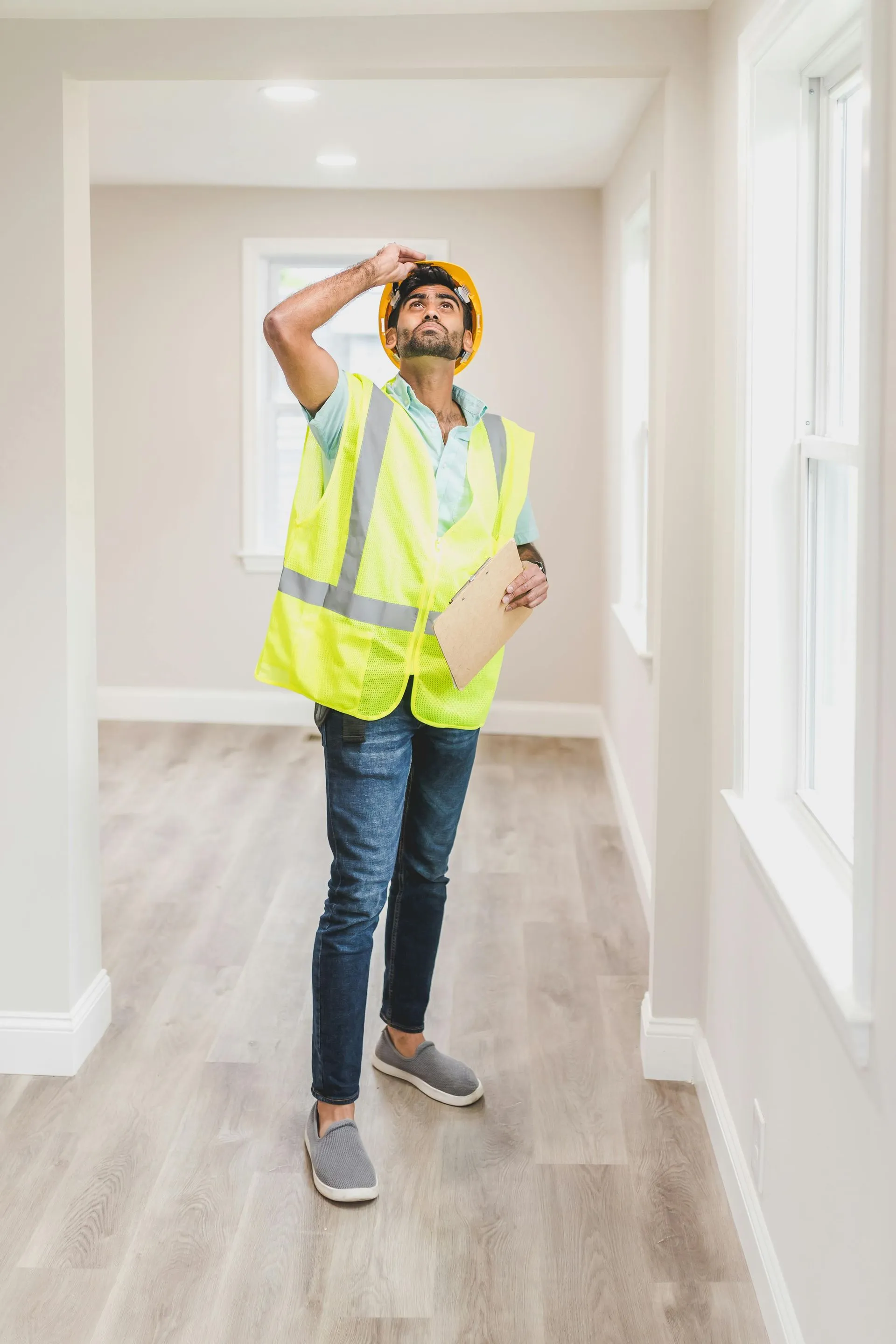 Building inspector in hard hat and high visibility vest checking a finished ceiling