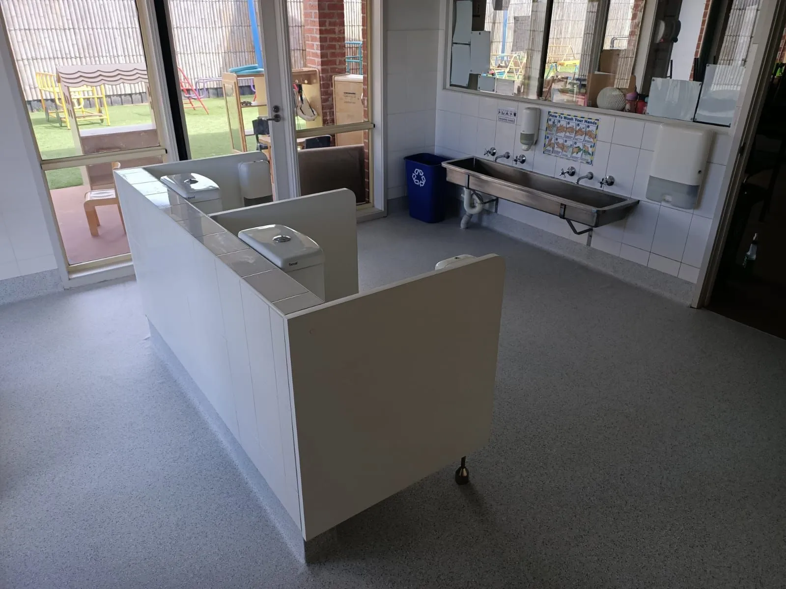 Childcare centre bathroom with child height trough basins and change bench