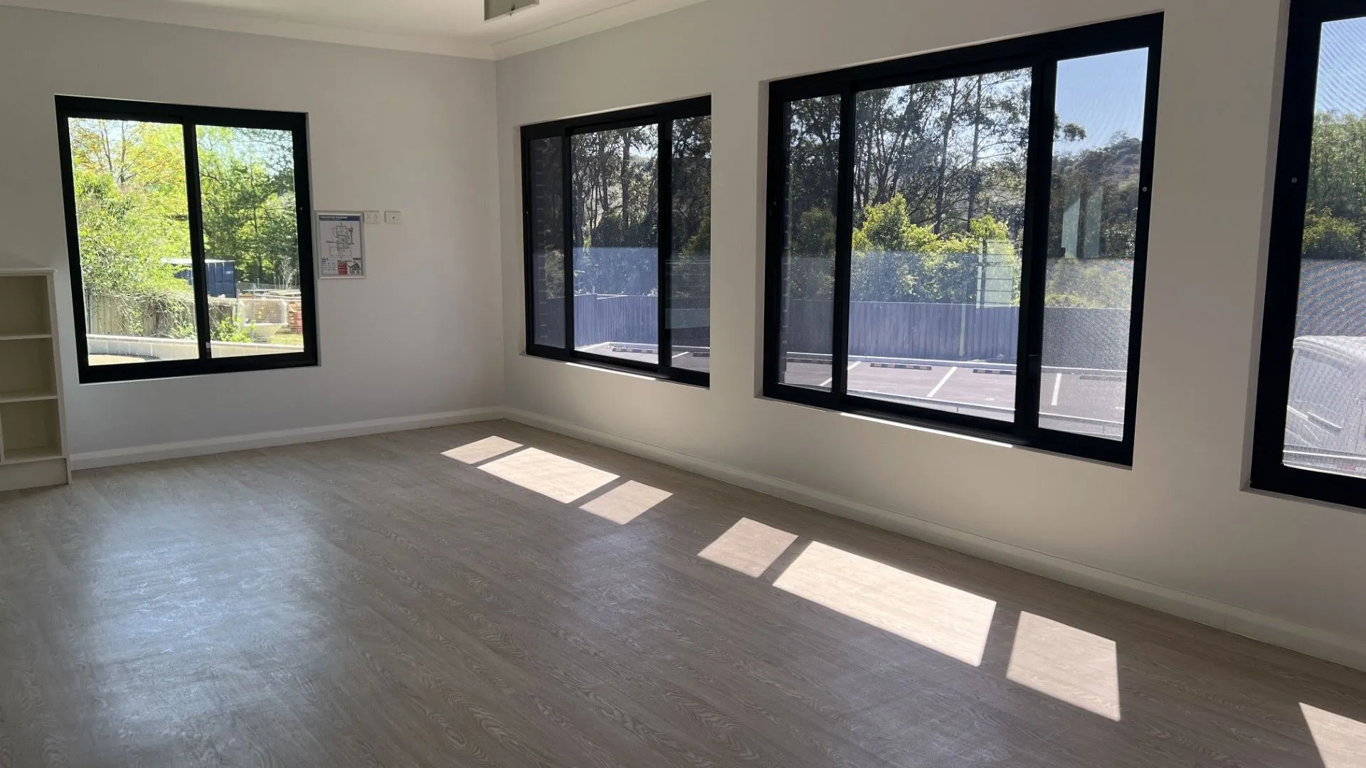 Childcare fitout playroom with large black framed windows and timber look flooring