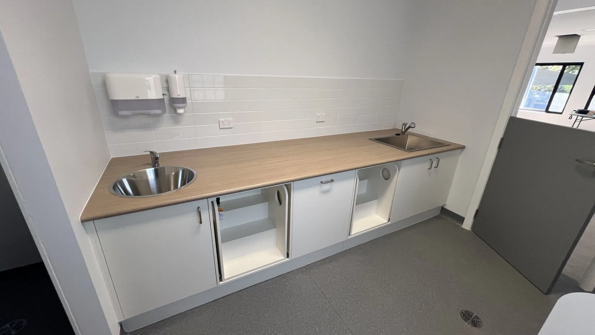Staff kitchenette with timber benchtop, white cabinetry and hand basin in a childcare fitout