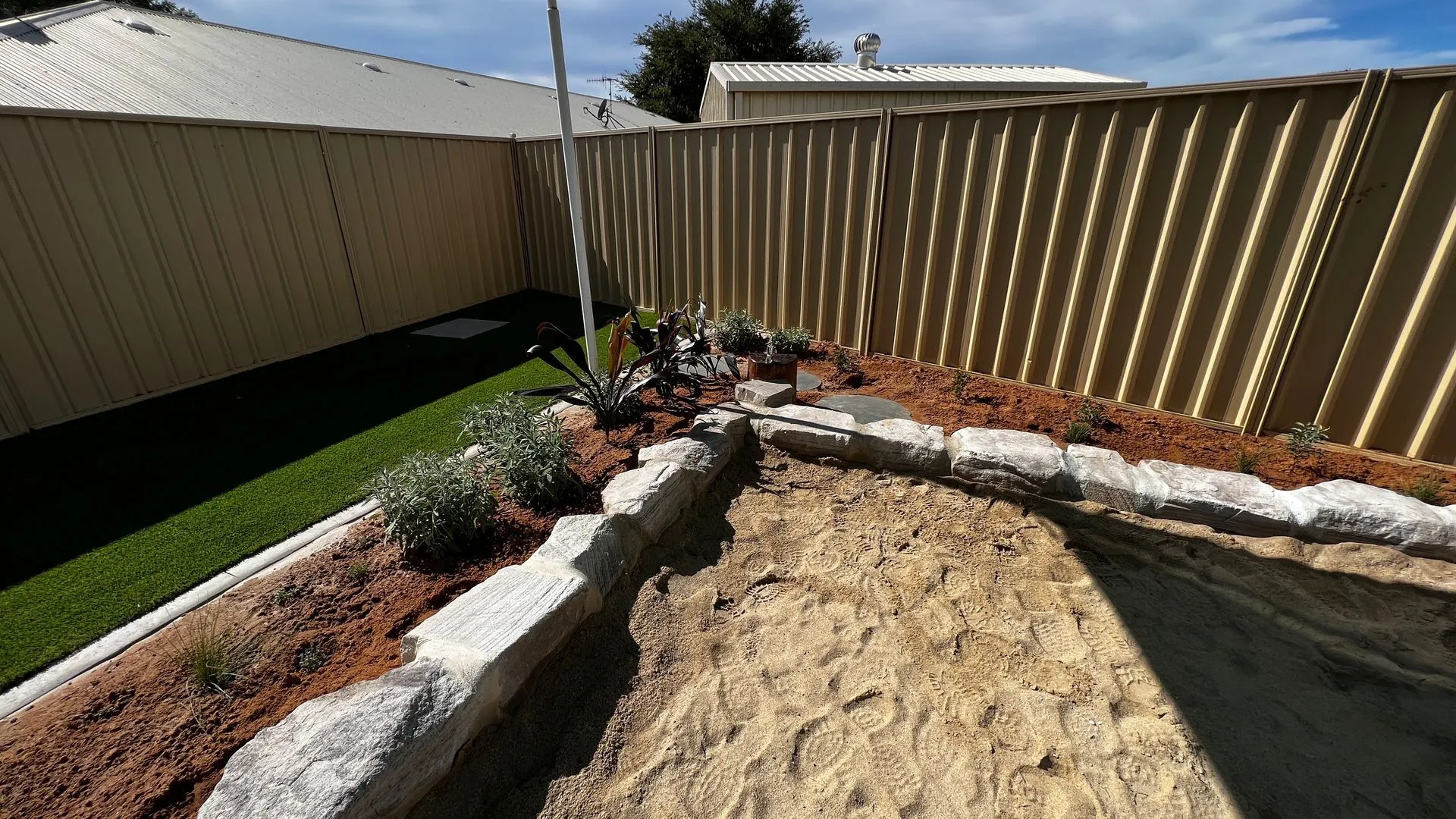 Childcare sandpit with sandstone block edging and native planting