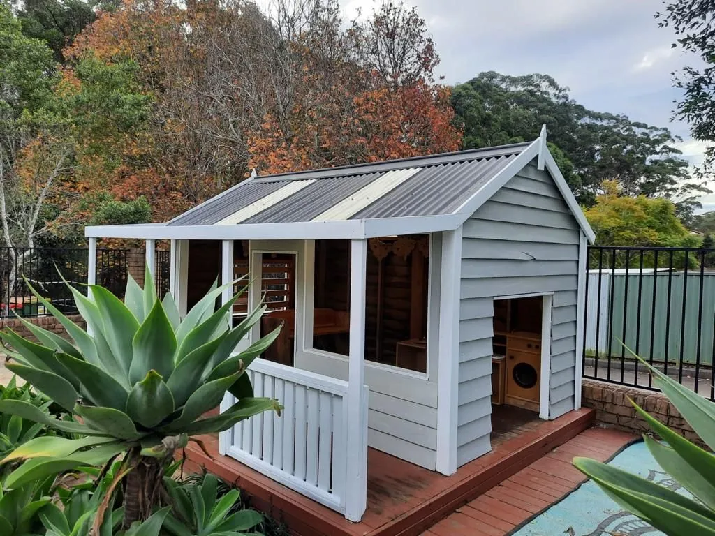 Weatherboard cubby house with verandah in a childcare centre playground