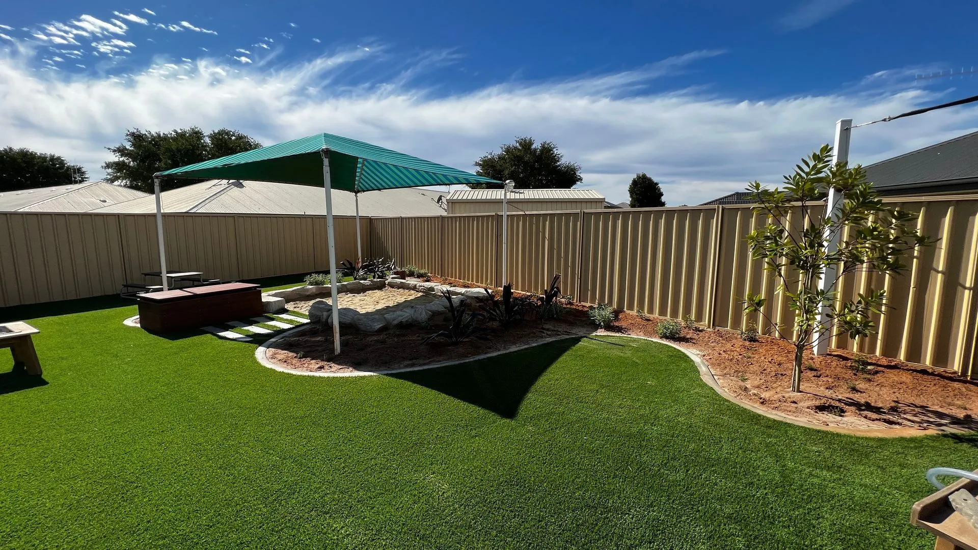 Childcare yard with a shade structure, synthetic turf and garden edging