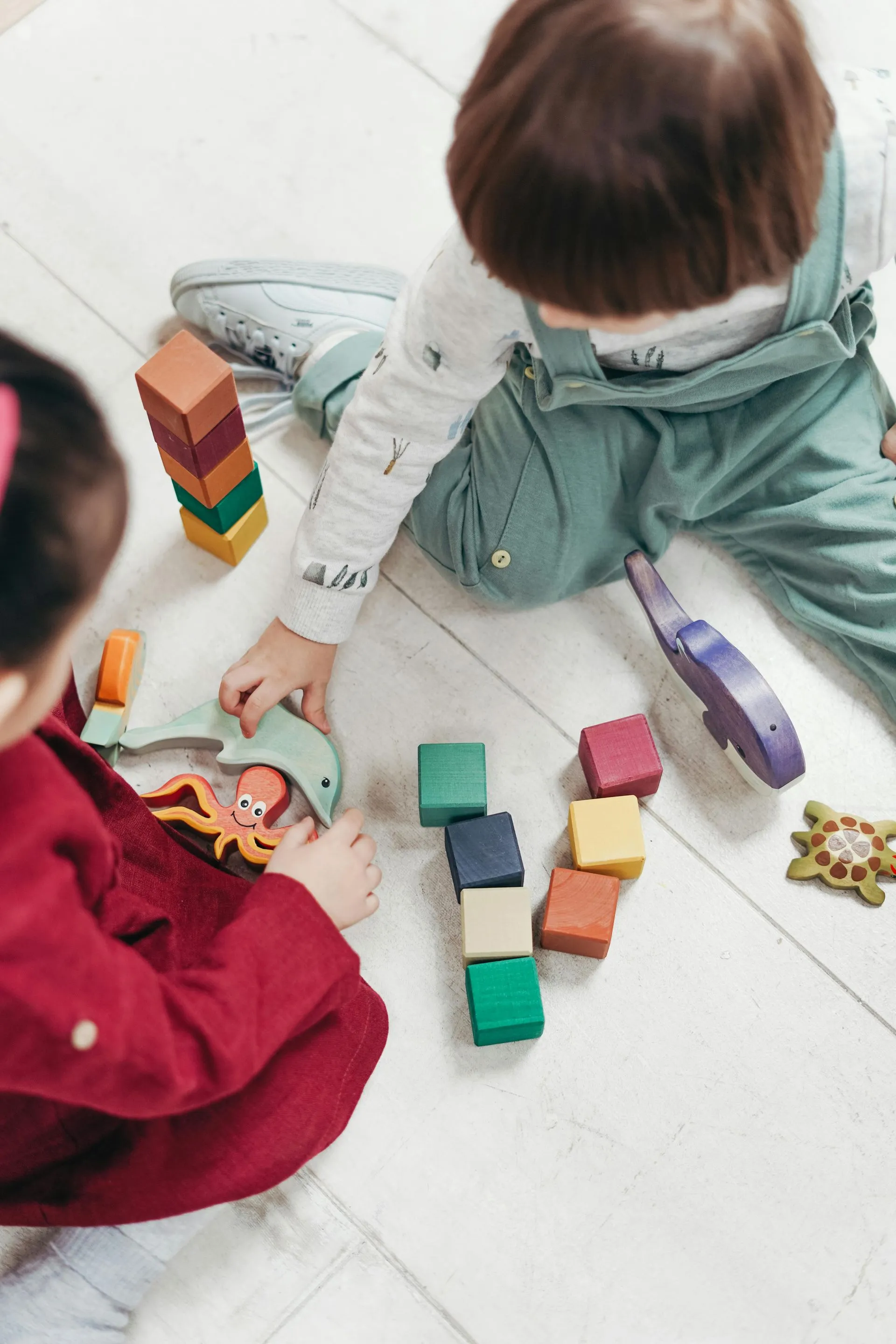 Young children playing with wooden building blocks on the floor