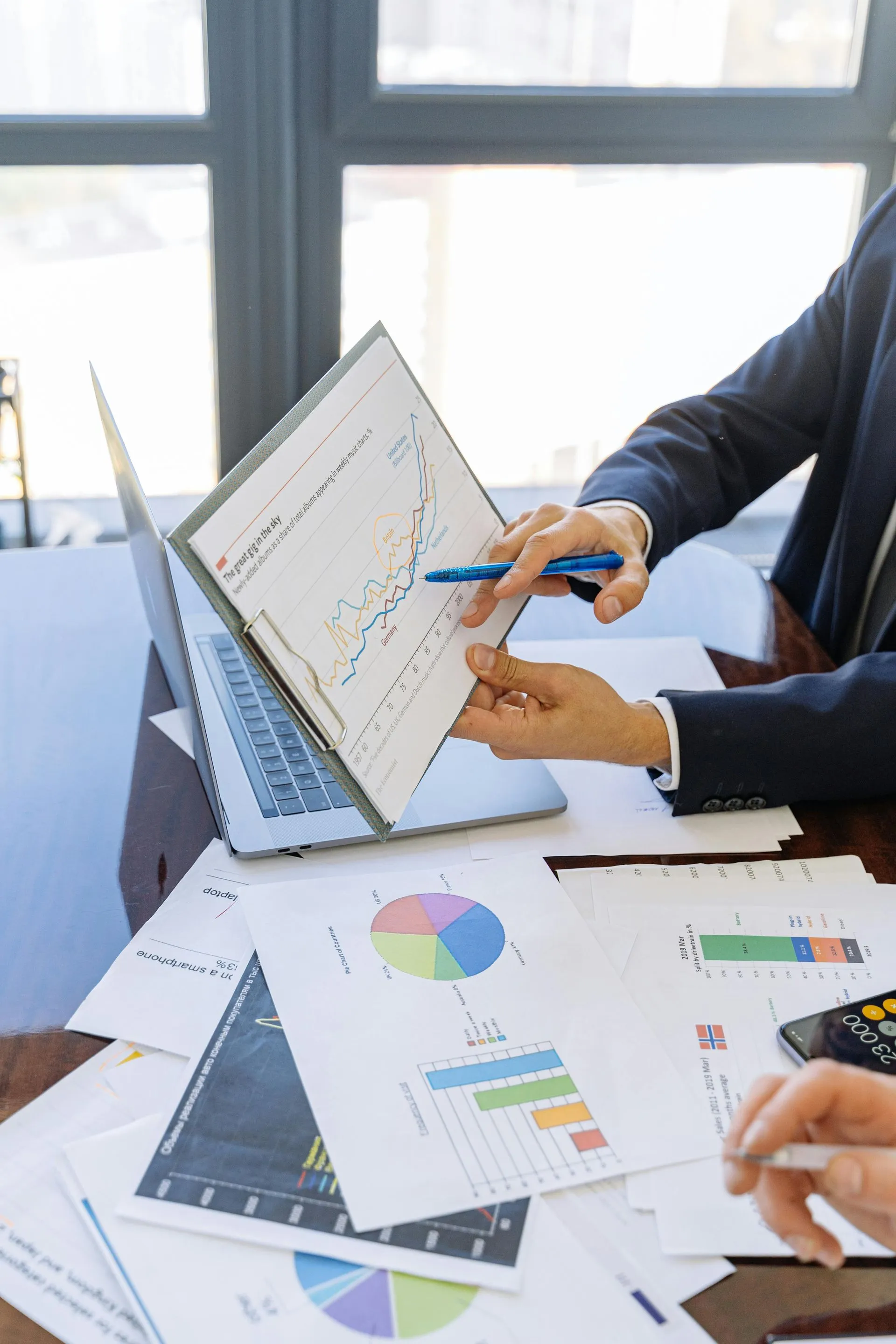 Compliance reports, charts and a laptop on a desk