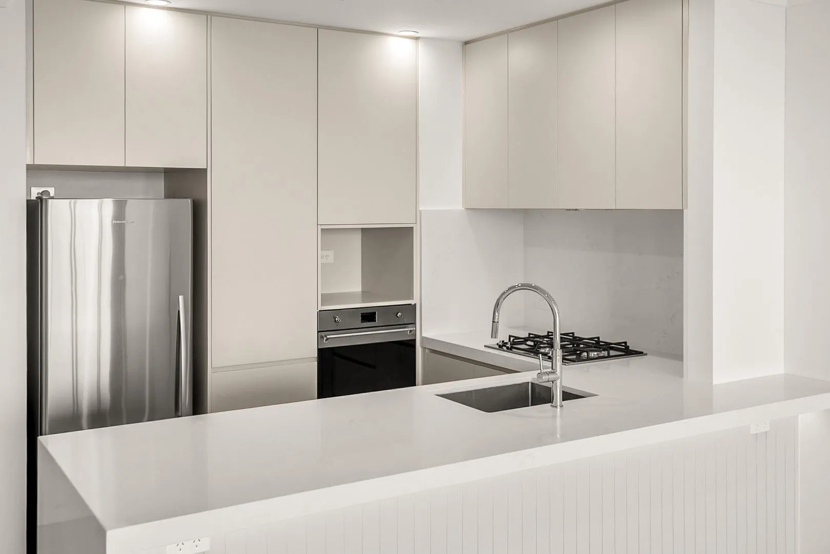Renovated kitchen with 60mm stone benchtops and polyurethane joinery in Cronulla beachfront apartment U907