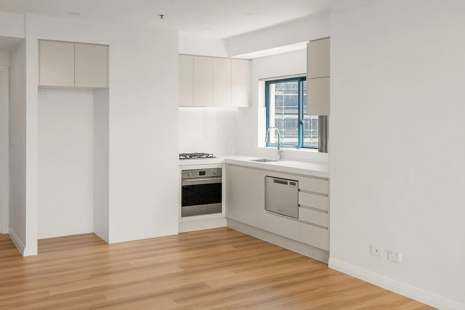 Renovated kitchen with stone benchtops and white joinery in Cronulla beachfront apartment U911