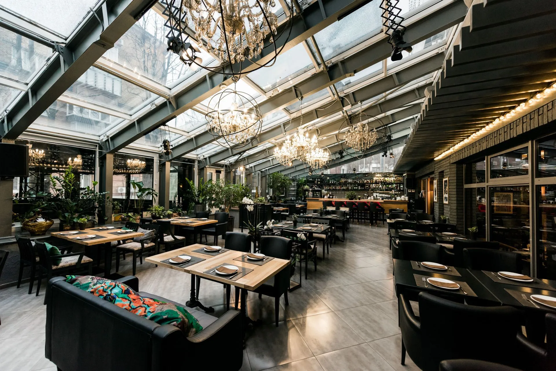 Glasshouse restaurant interior with chandeliers, timber tables and lounge seating
