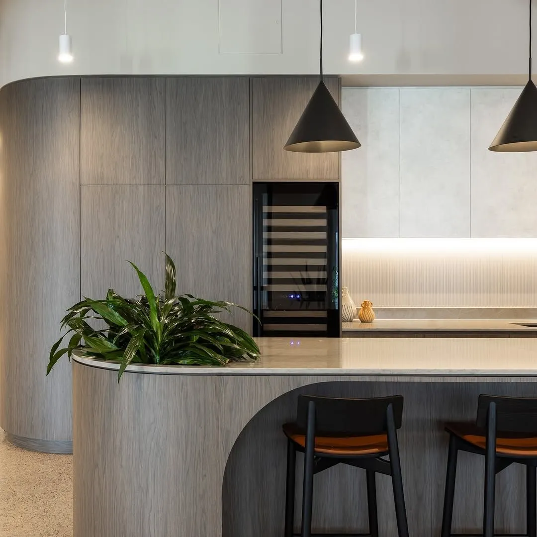 Curved office kitchen island with planter, wine fridge and pendant lighting