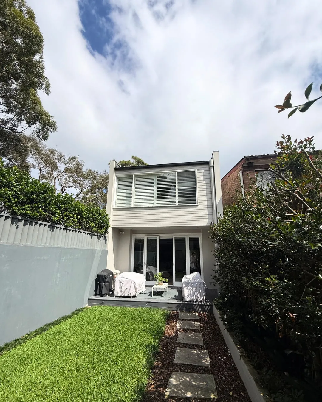 Rear of a heritage home in Randwick with lawn and a stepping stone path, before renovation