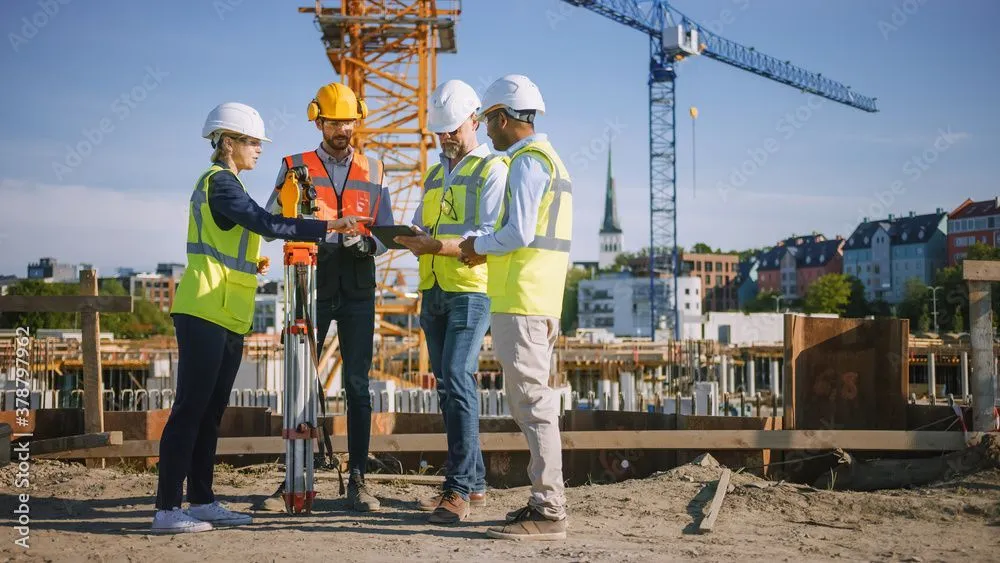 Construction team with a surveying instrument discussing site safety and setout